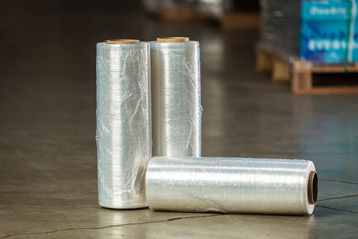 Three rolls of plastic wrap on a warehouse floor.